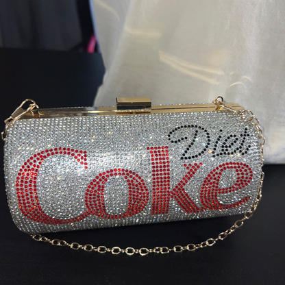 Silver clutch with 'Diet Coke' text in rhinestones on a dark background