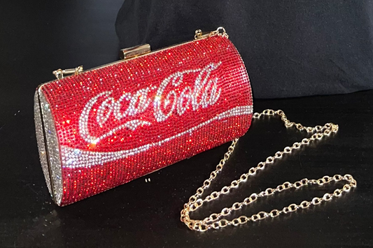 Red clutch with Coca-Cola logo and rhinestone details on a black background